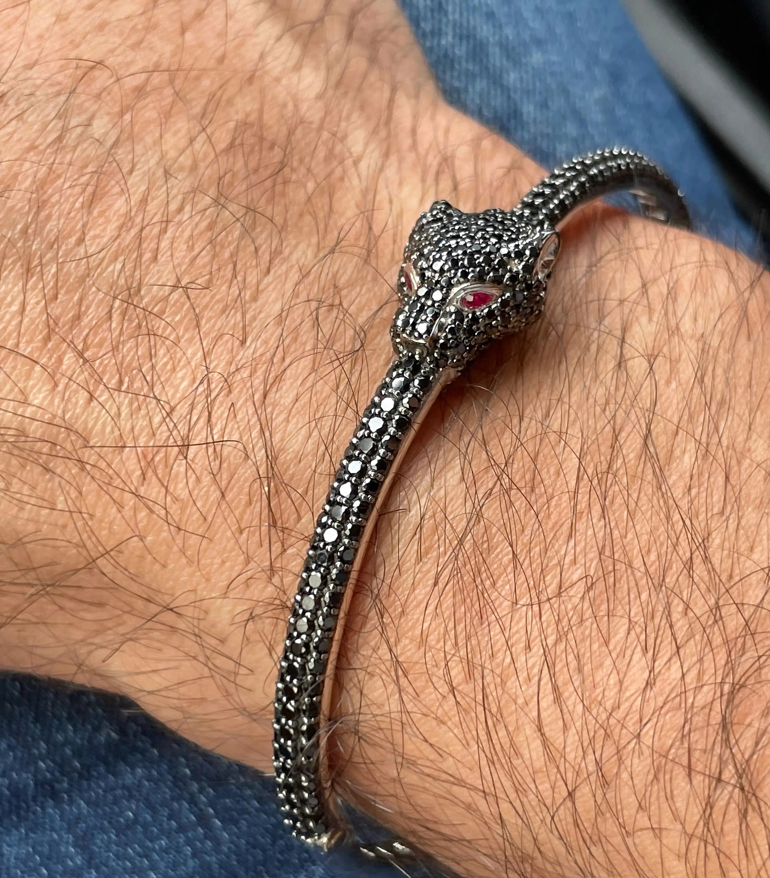 Silver panther bracelet on a wrist with a blue fabric background