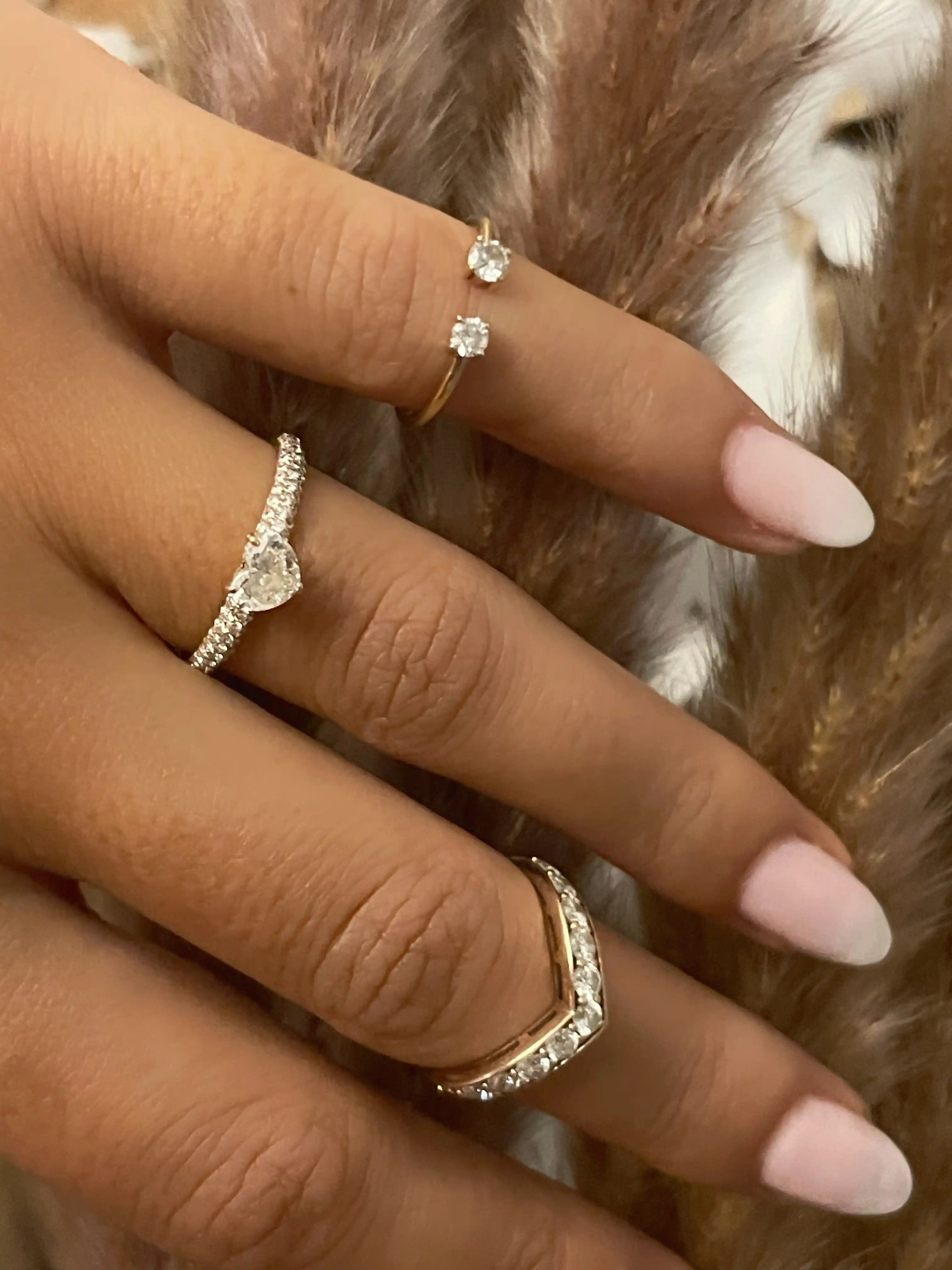 Close-up of a hand wearing three diamond rings with a soft focus background