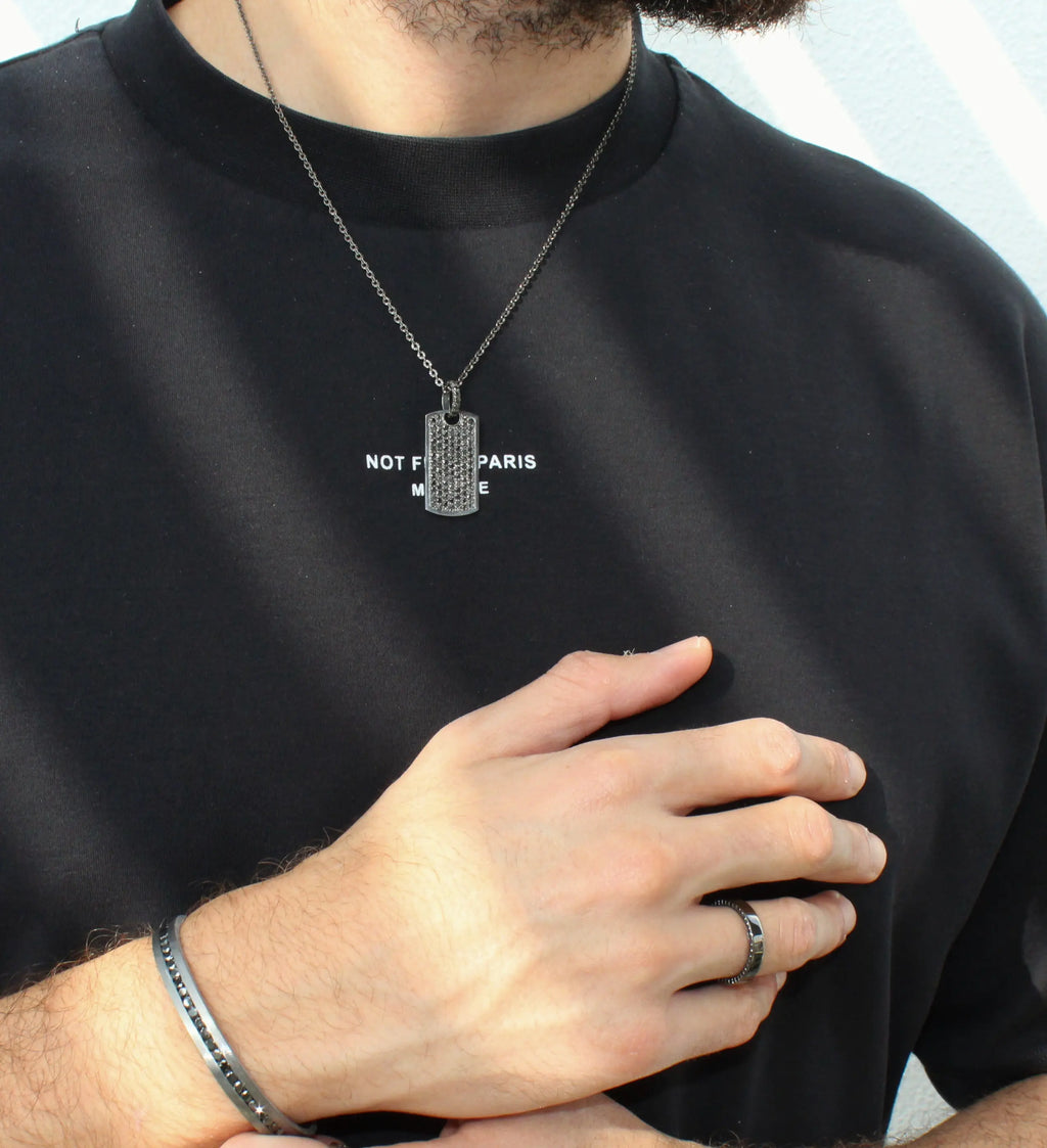 Person wearing a black shirt with text, silver necklace, and ring.